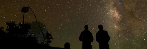 Two people looking up at a dark, starry sky.