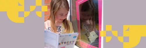 A young girl with blonde hair reads a booklet with Street Museum written on the front