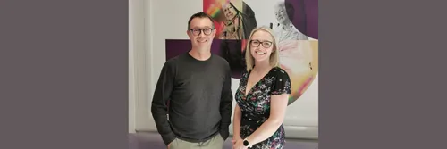 Dr Toni Williams (right) and Professor Martin Roderick (left) smiling in front of a 91 banner