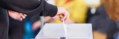 A hand placing a polling card into a box