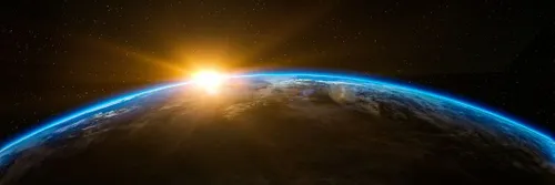 The Sun rising above the horizon of the Earth as seen from space.