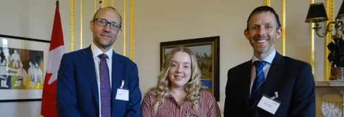 A student standing with two representatives