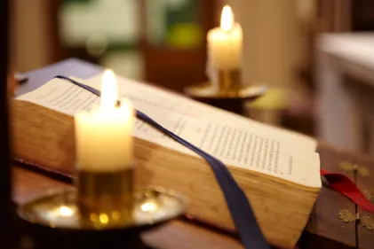 Close-up of church candle with book behind