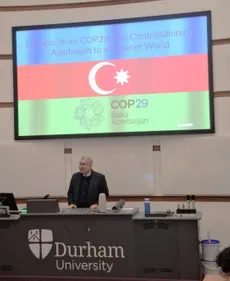 The Azerbaijani Ambassador standing in front of a PowerPoint presentation