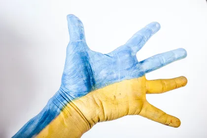 The open hand of an adult painted half yellow and half blue