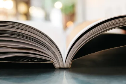 A close up side view of an open book with a blurred light background