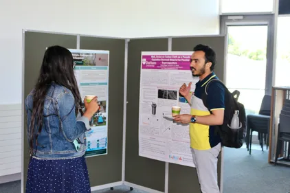Mian Faisal with his research poster, talking to another student
