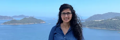 An image of Assistant Professor Renu Singh with the ocean and mountains in the background.