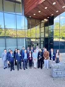 A group photo of international participants of a conference in front of a glass building of the Durham Law School.