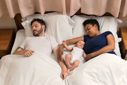 Couple laid in bed with baby
