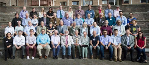 Symposium attendees smiling for a group photograph outside of Collingwood College.