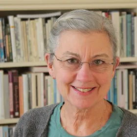 A smiling woman with grey hair and glasses
