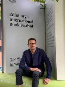 Nick Barley in front of Edinburgh International Book Festival marketing materials