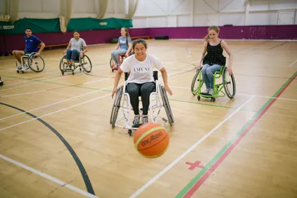 Four students participating in wheelchair basketball with one student in pursuit of the ball.