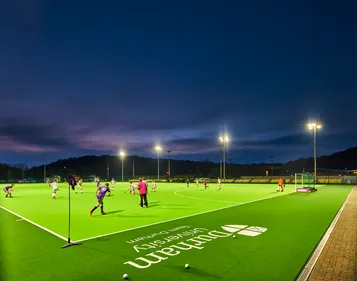 Students playing hockey outdoors on a sports pitch