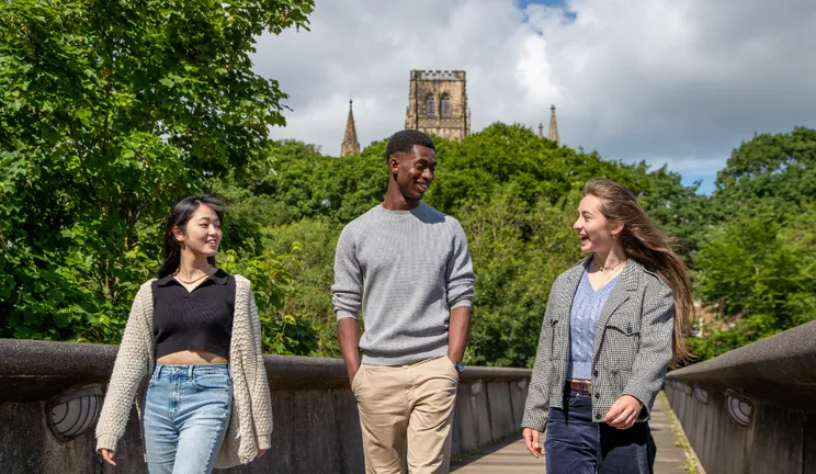 Three students walking across a bridge