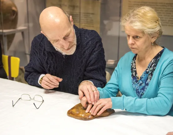 People taking part in an accessible touch tour event and handling museum objects.