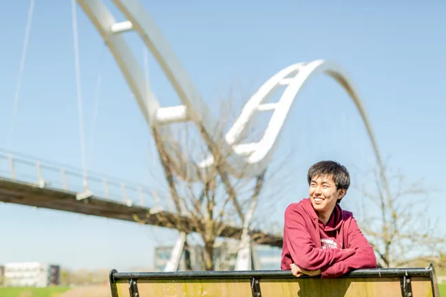 An international student in front of the Millennium Footbridge, which overlooks Queens Campus, Stockton