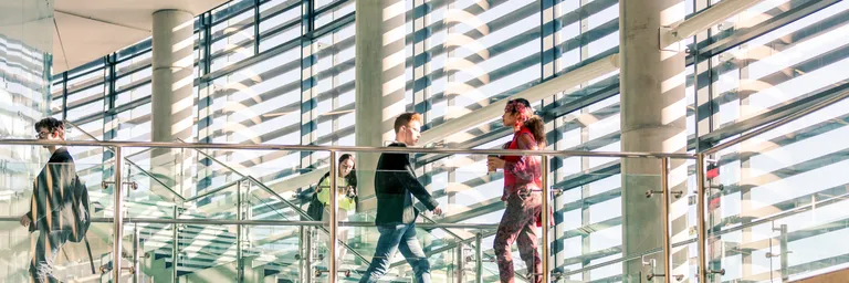 two students pass each other in front of the glass windows in the bill bryson library
