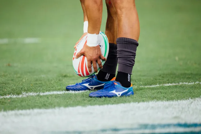 Close-up of a male rugby player holding a rugby ball by their feet