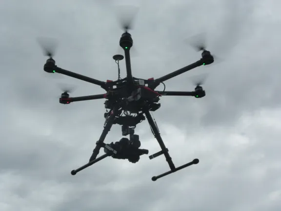 a UAV or drone with a camera attached flying in cloudy skies