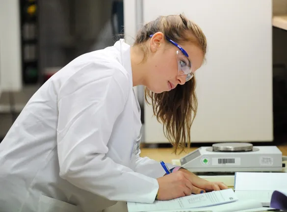 A student writing at a desk in a Chemistry laboratory session