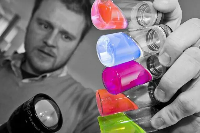 Man shining a torch on coloured test tubes