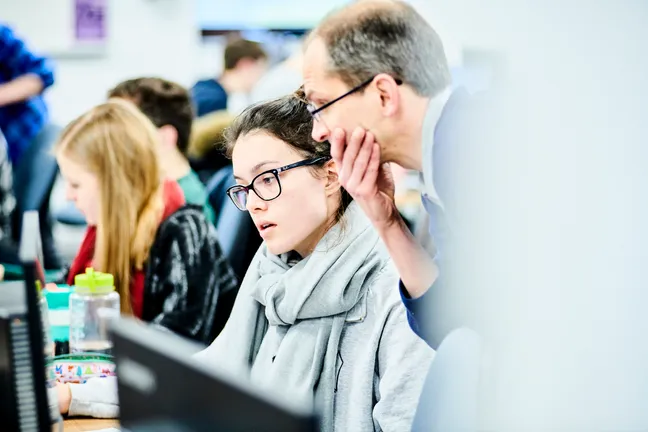 Tutor helping a student on a computer.