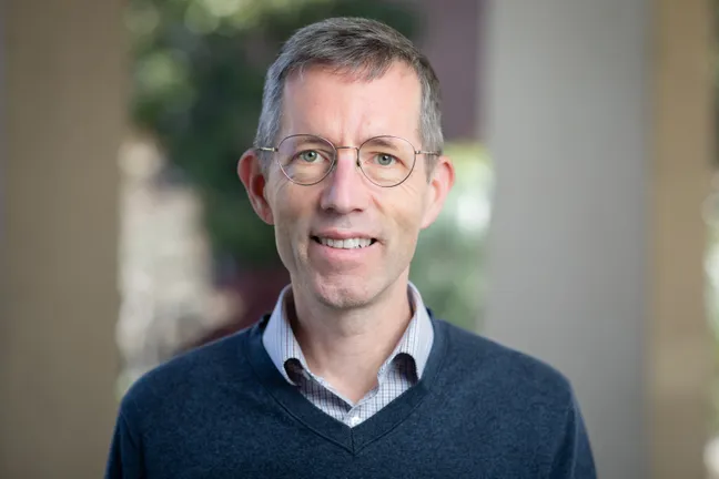 A man with short hair and glasses