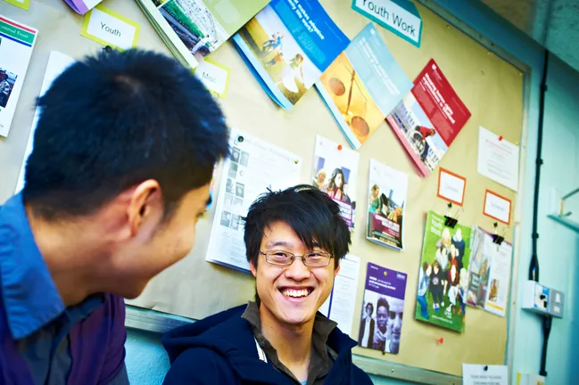 A student smiling in conversation with another classmate