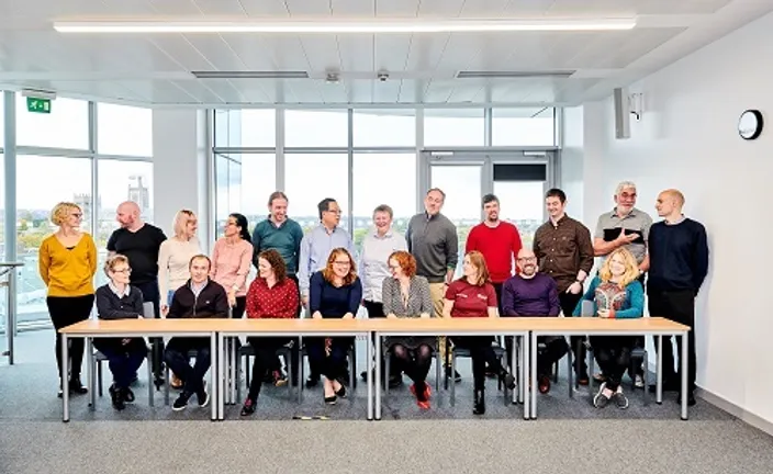 Department staff sitting and standing around a table for a group photo