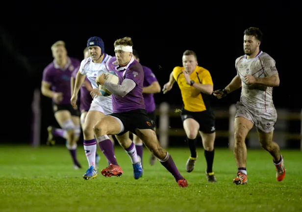 Group of men playing a game of rugby on a pitch