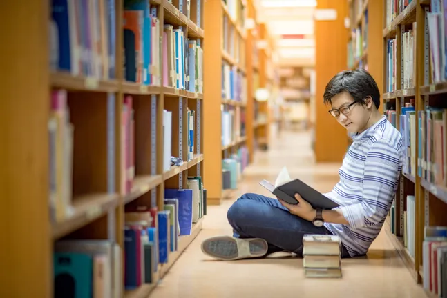 Student sitting by bookshelves filled with books