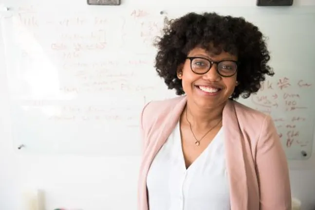 A young student wearing glasses and smiling on a white background