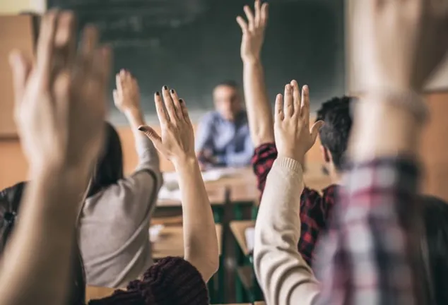 Students in classroom with hands up