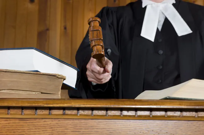Judge In Traditional Court Robes Using the Gavel