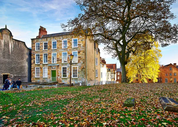 A period building with a tree and autumnal leaves