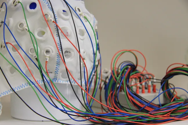 An EEG cap with a lot of wires connected to an interface box.