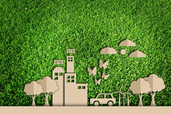 Cardboard cut out town and car on a green background