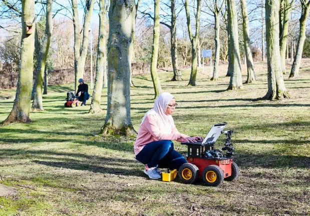 Students working outside on laptops on remote controlled vehicles