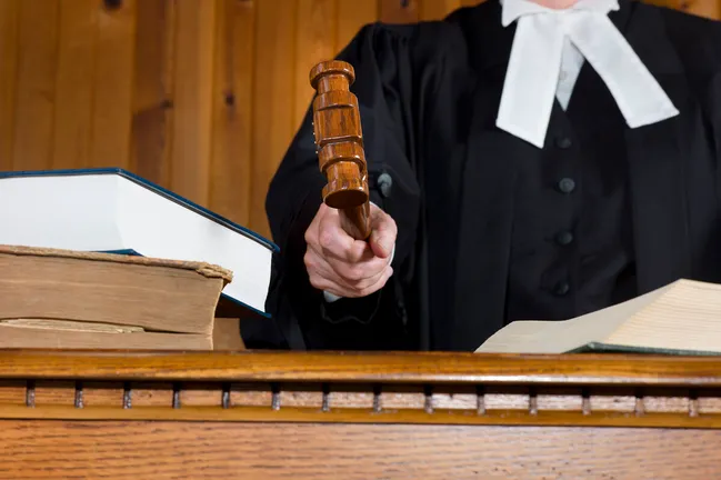 Judge in traditional court robes using gavel
