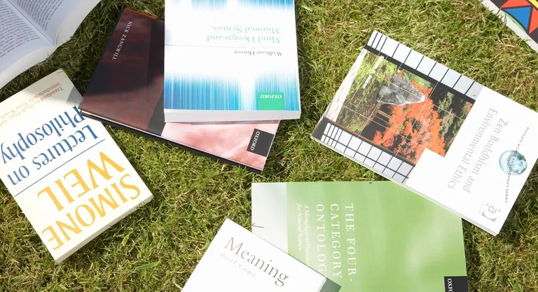 Several philosophy books lying on the grass