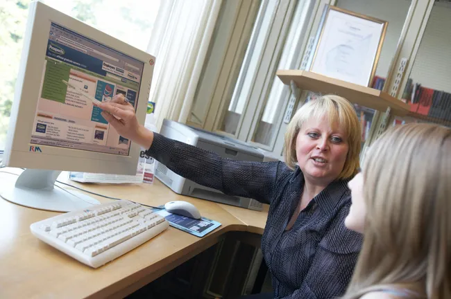 A Careers and Employability advisor assisting a student at a computer