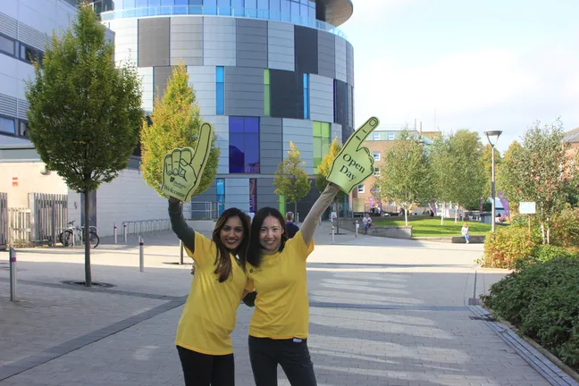 Two Durham ambassadors dressed in yellow holding up foam fingers during an open day