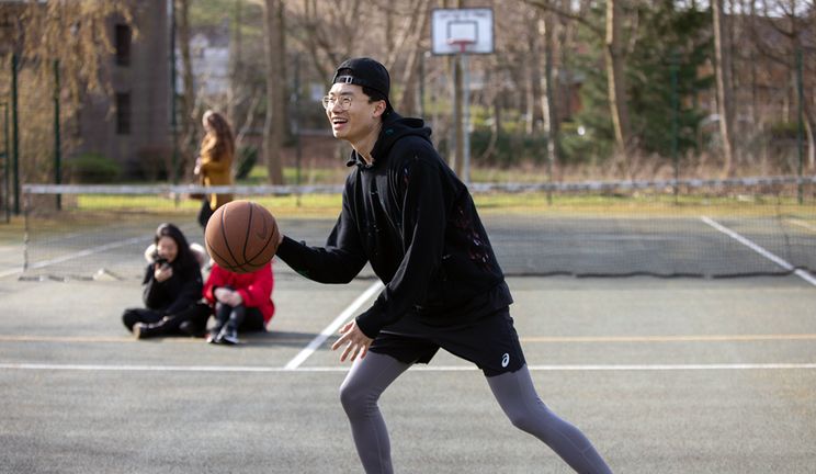 A student plays basketball on the all-weather sports court