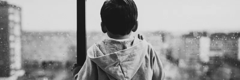 Backview of child waiting by a glass window