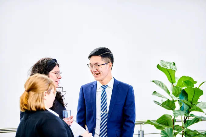 A group of three smartly dressed men and women talking to each other and smiling