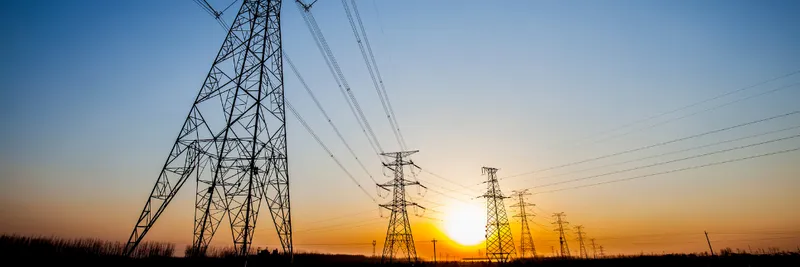 Electricity pylons with sun setting behind them
