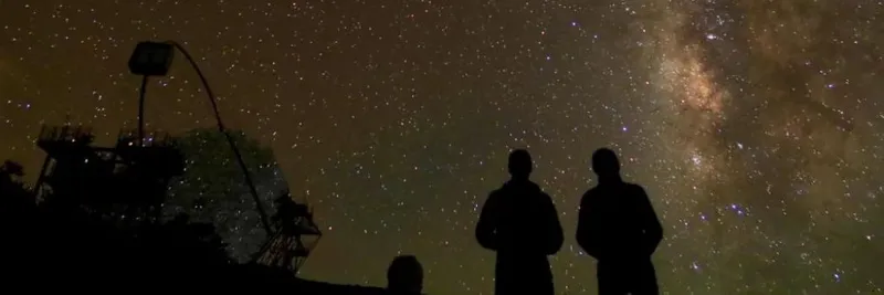 Two people looking up at a dark, starry sky.