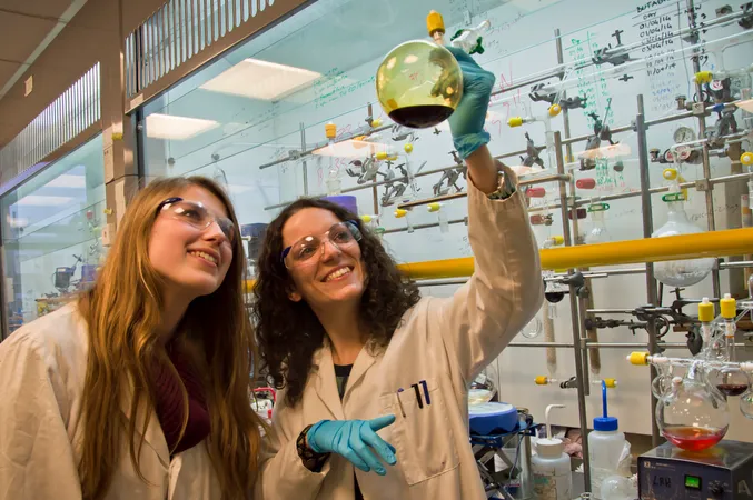 Postgraduate students in lab looking at chemical in bottle